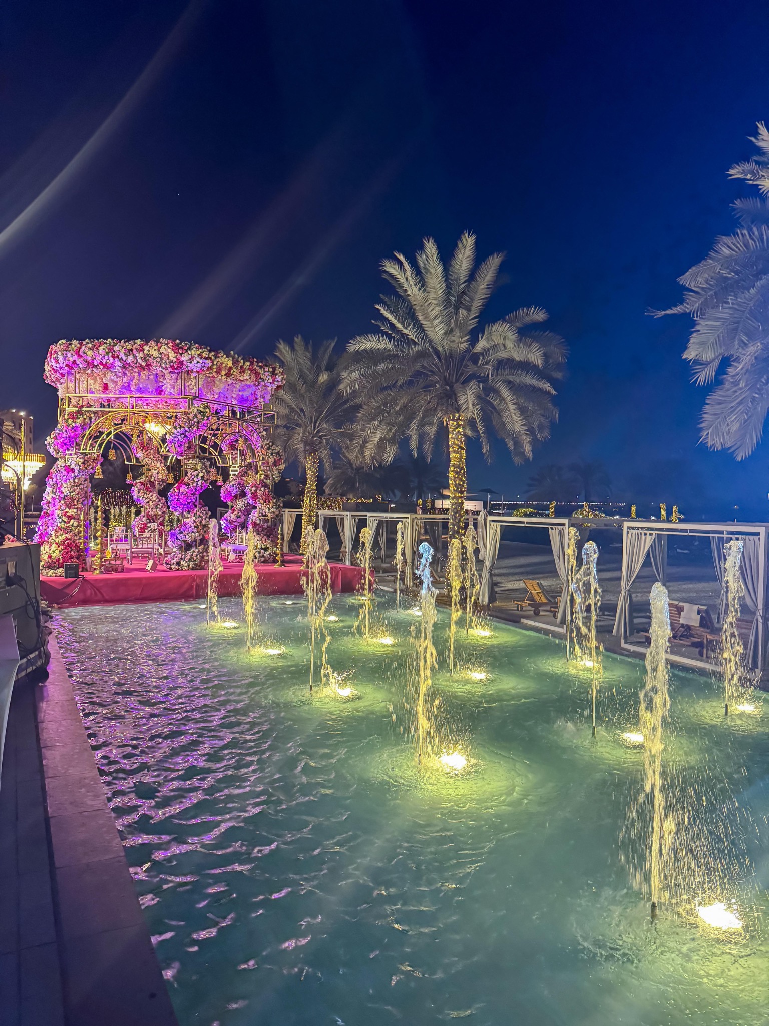 Night-time destination wedding beside a pool with floral stage
